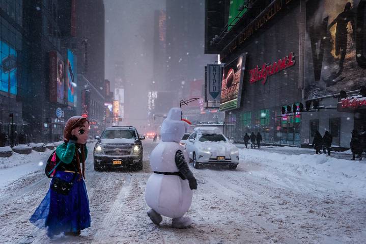 This is a photo of two Times Square characters crossing the street in a snow storm.